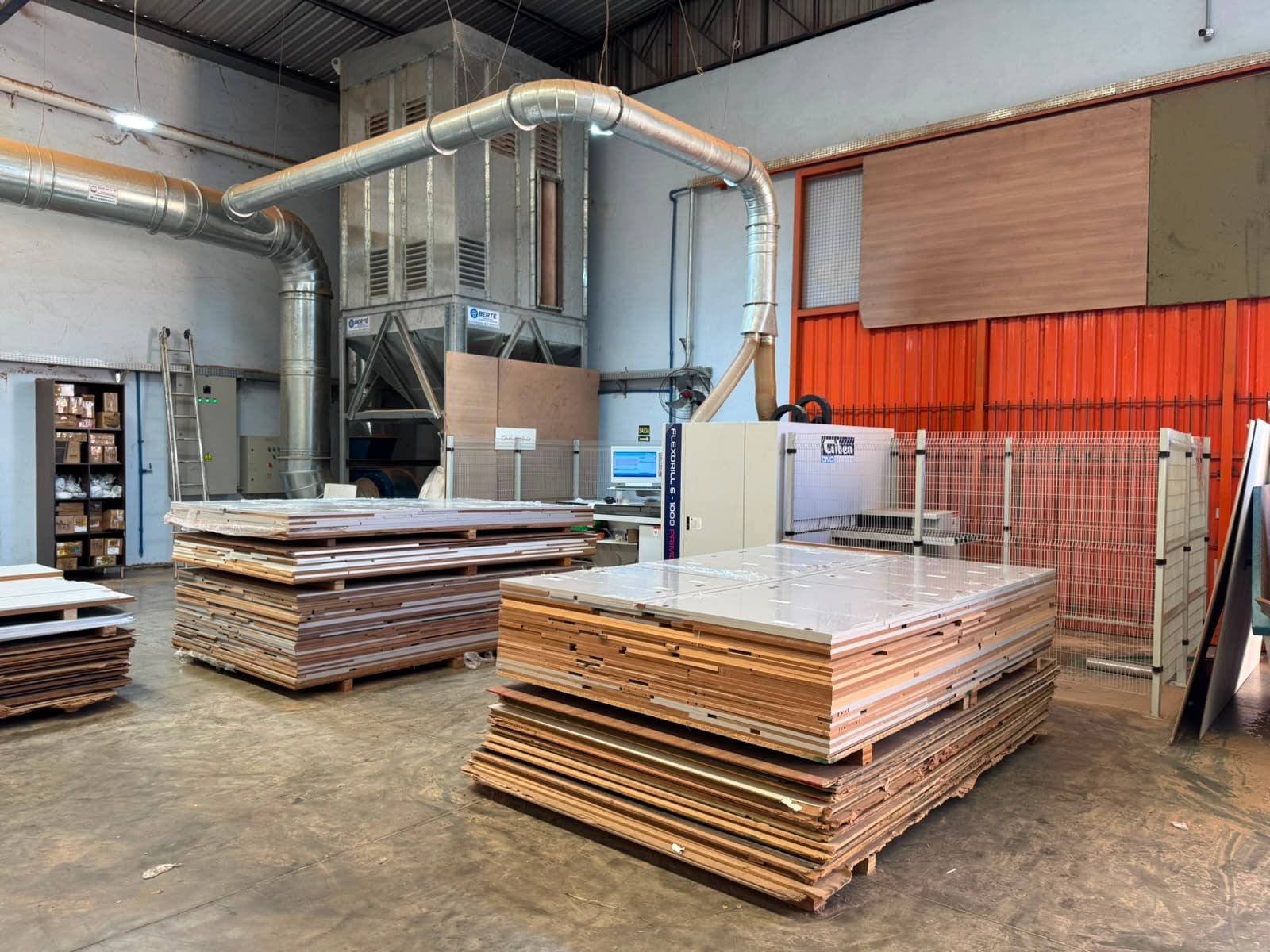 Furadeira CNC Giben Flexdrill 6-1000 ao lado das pilhas de peças aguardando furação.